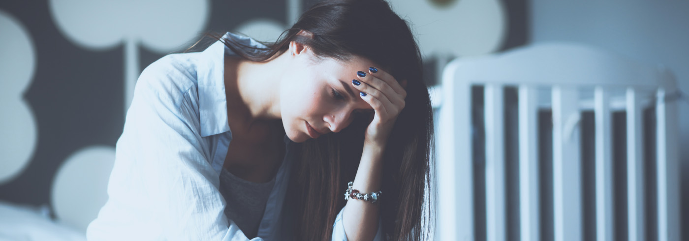 Woman looking sadly at baby clothes