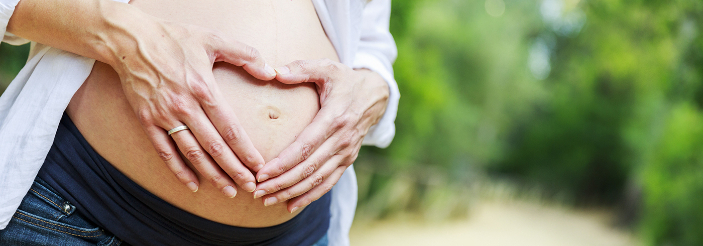 A woman holding her pregnant belly.