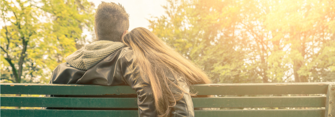 Young couple sitting on a park bench talking.