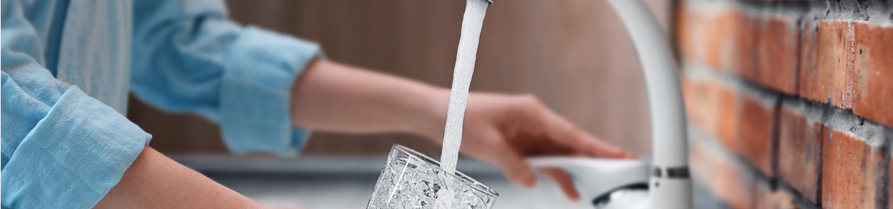 Woman filling a glass of water from the kitchen tap