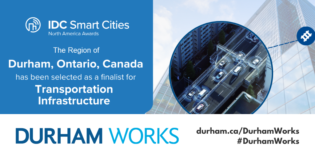 A banner with a light blue background on the left with white text reading IDC Smart Cities North America Awards The Region of Durham, Ontario, Canada has been selected as a finalist for Transportation Infrastructure. A graphic of buildings and roads with cars on it is shown on the right side of the graphic. There’s also a Durham Works branded white banner with black text reading durham.ca/DurhamWorks #DurhamWorks