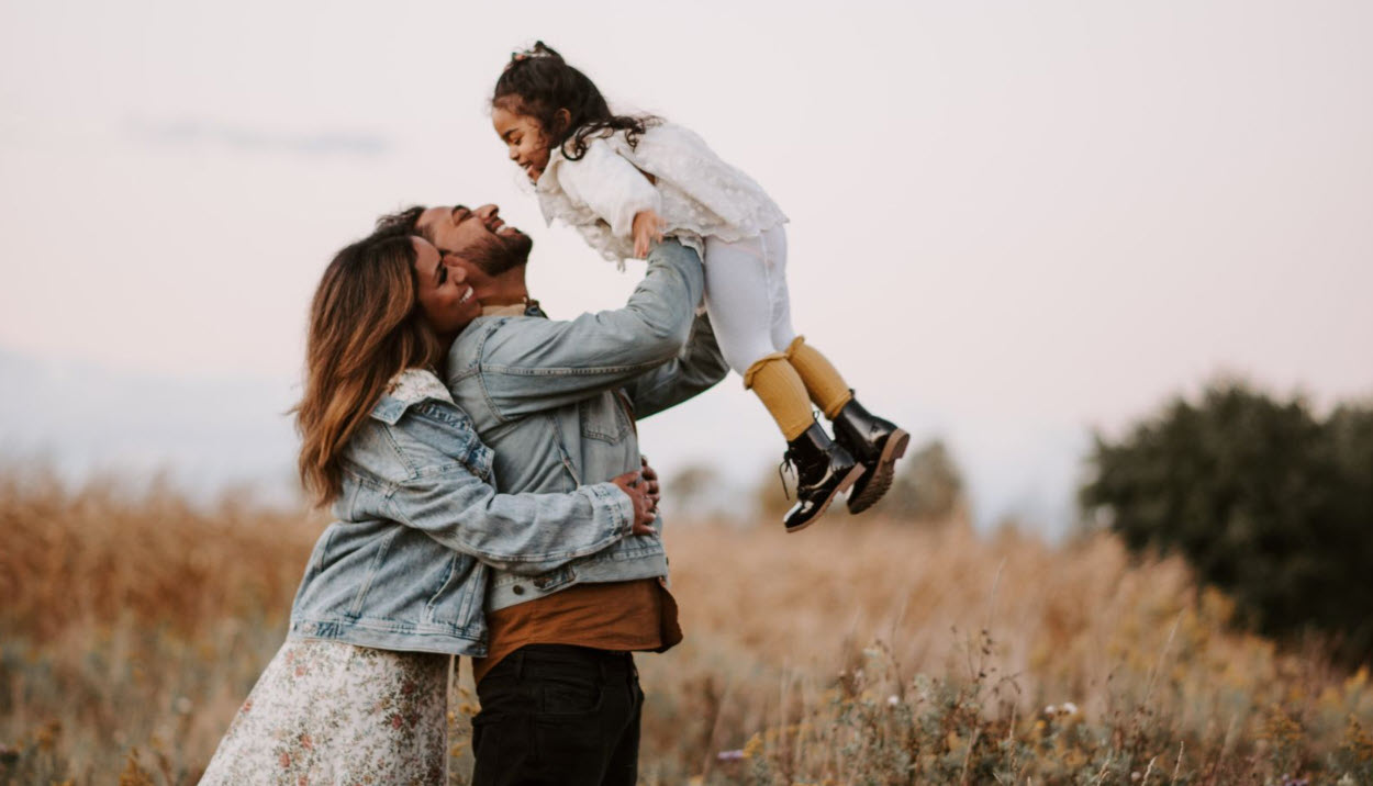 Father holding daughter up in his arms while mother looks on