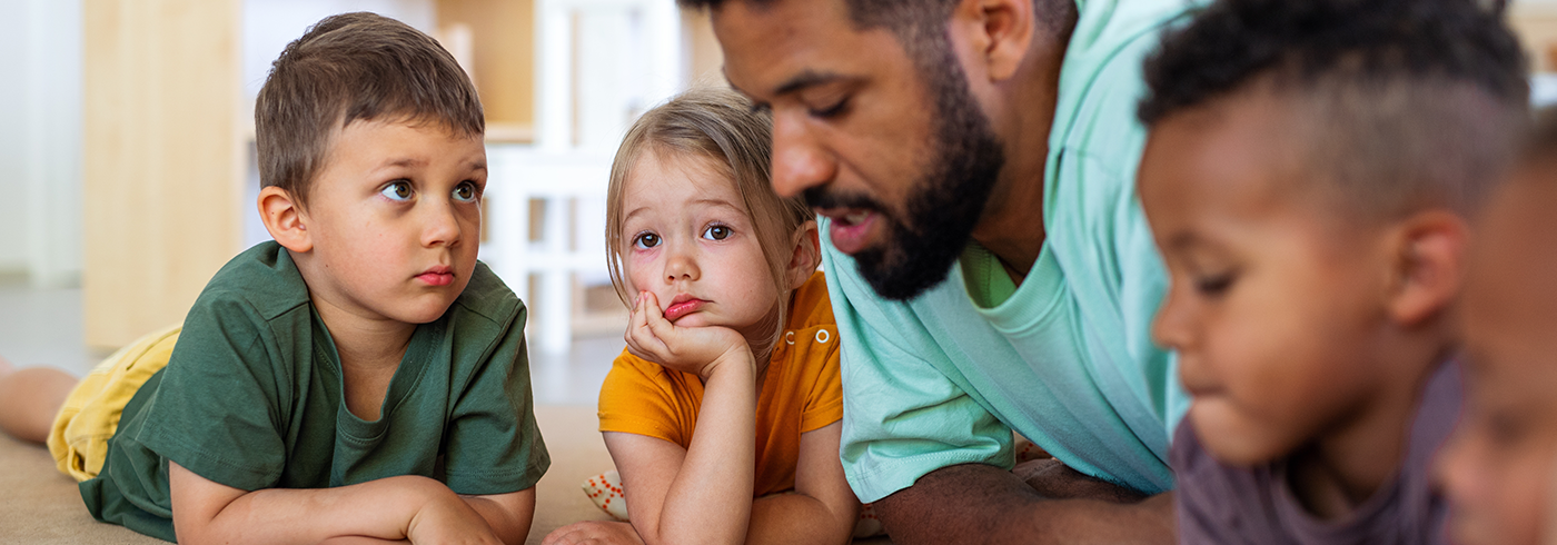 Male teacher reading with group of children