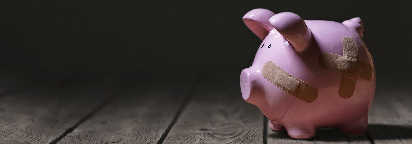 Piggy bank with several band-aids where it has been repaired