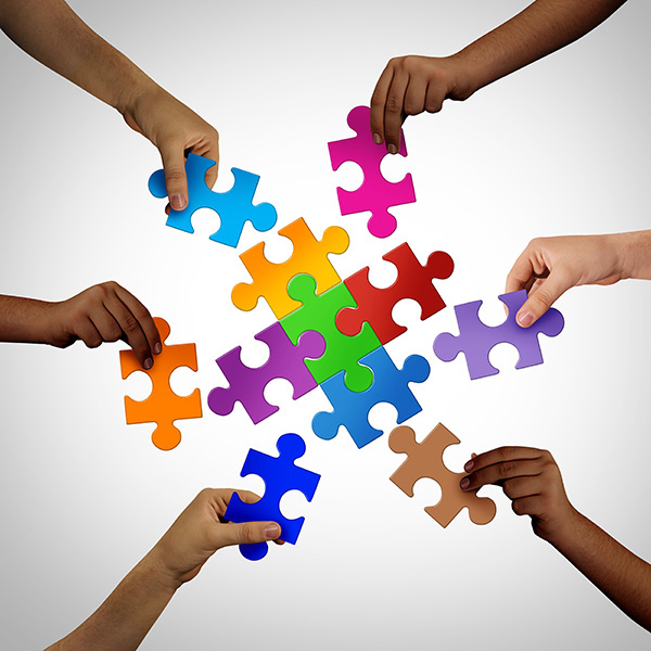 Hands holding coloured puzzle pieces