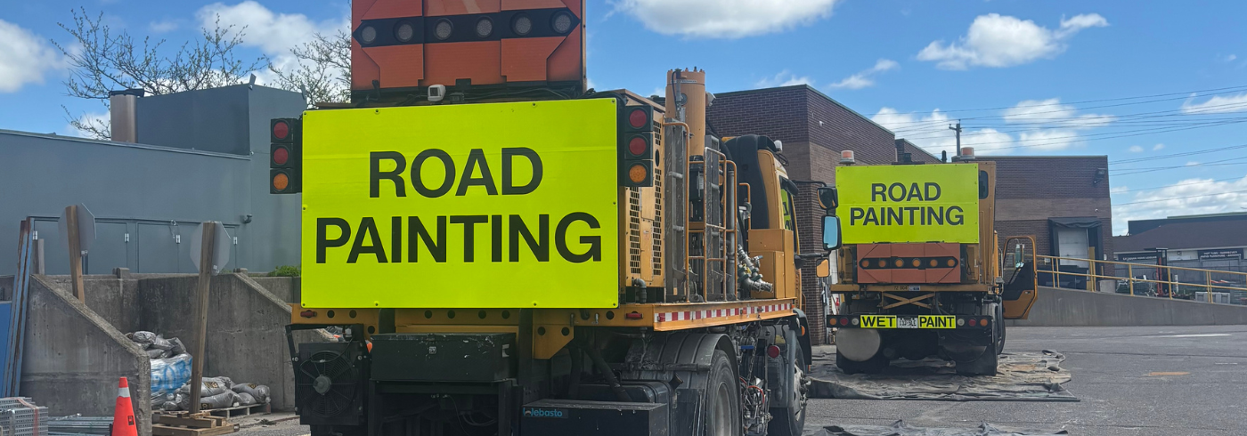 Two road painting trucks with Road Painting signs on the back.