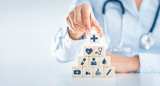 A person with a stethoscope builds a block tower with medical icons