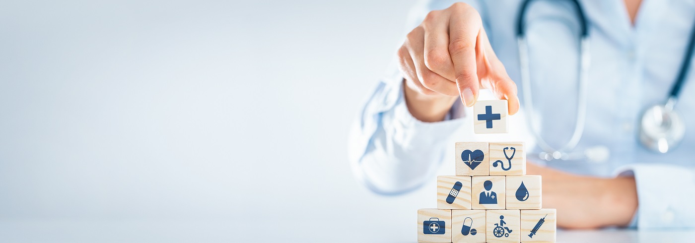 A person with a stethoscope builds a block tower with medical icons