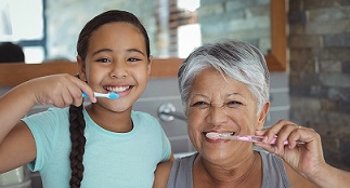 Grandmother and granddaughter brushing their teeth together