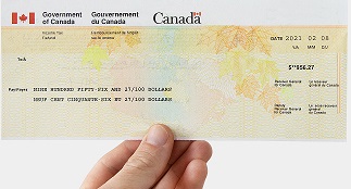 A hand holding a Government of Canada benefits cheque