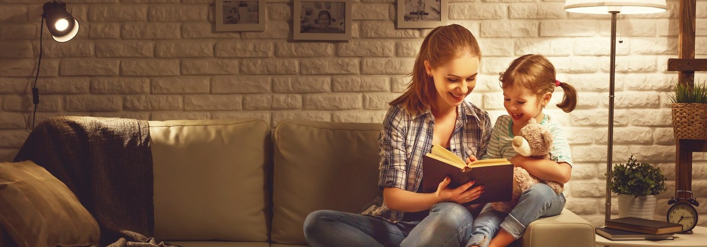 Mother and daughter sitting on couch reading