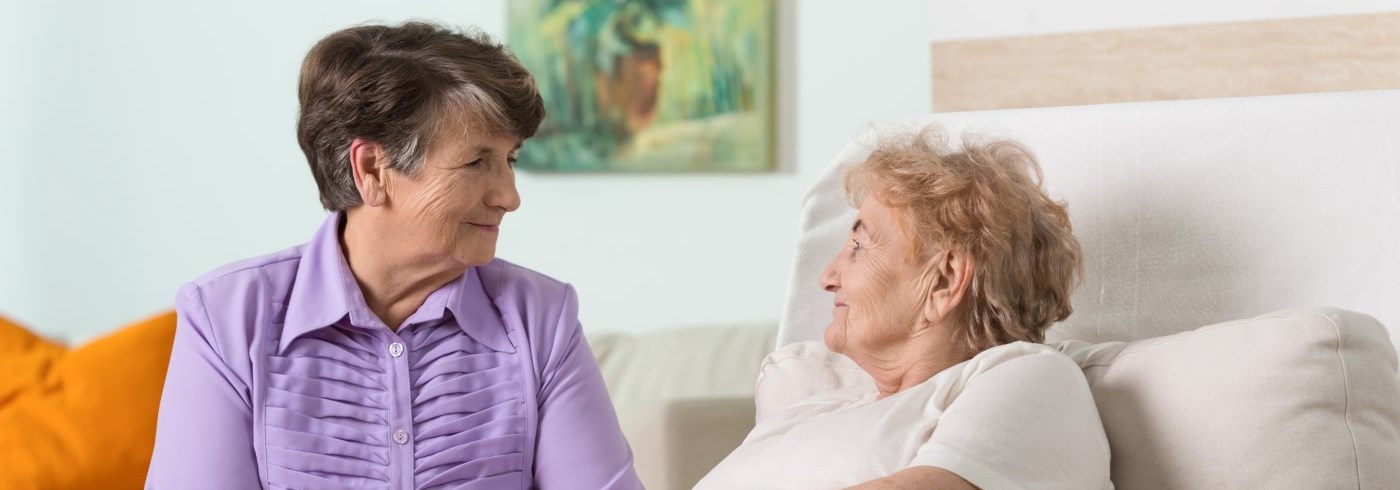 Woman visiting elderly lady in bed