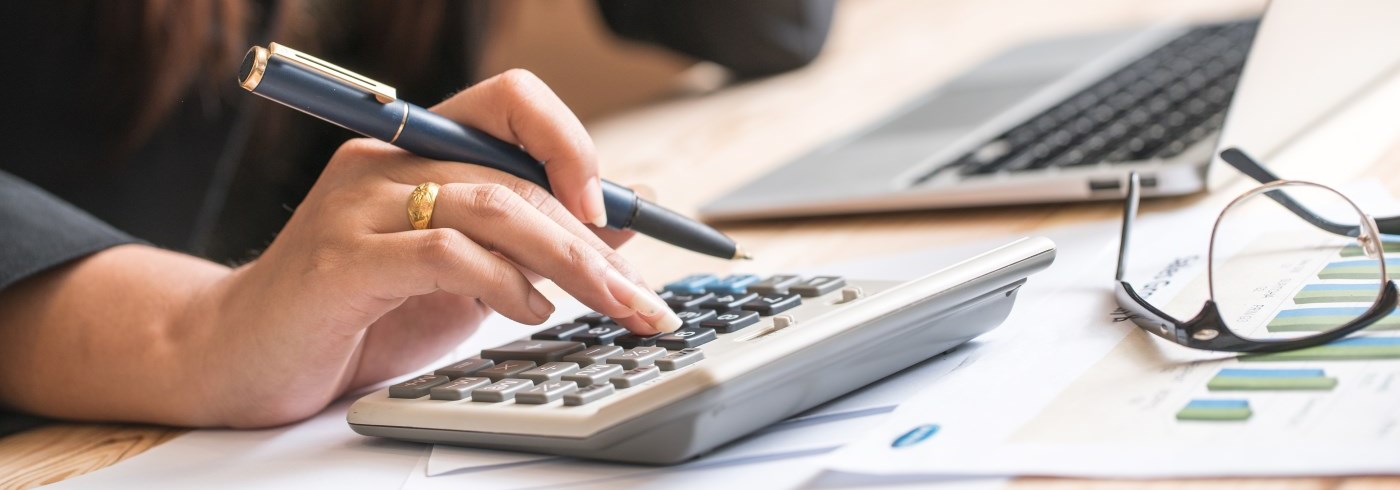 Hand holding pen while using calculator