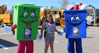 Girl standing with waste management mascots