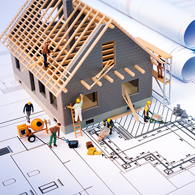 A construction team working to build a home on top of a blueprint drawing