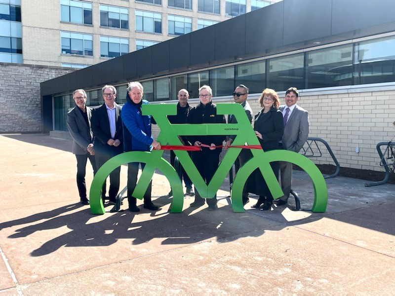 People standing in front of a green bike rack, in front of Regional headquarters.