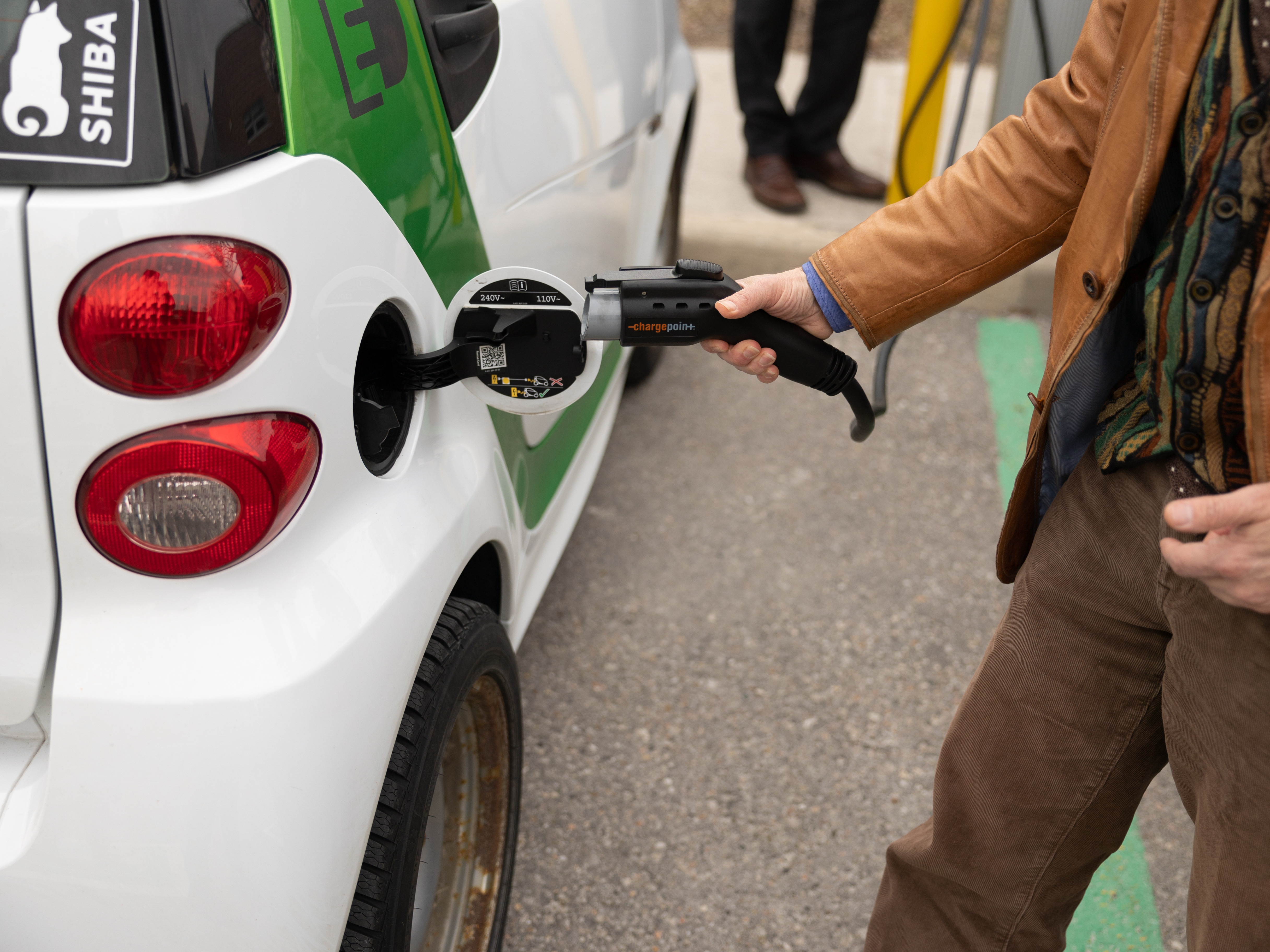 A person holding an electric vehicle charging cable as they prepare to plug it in.