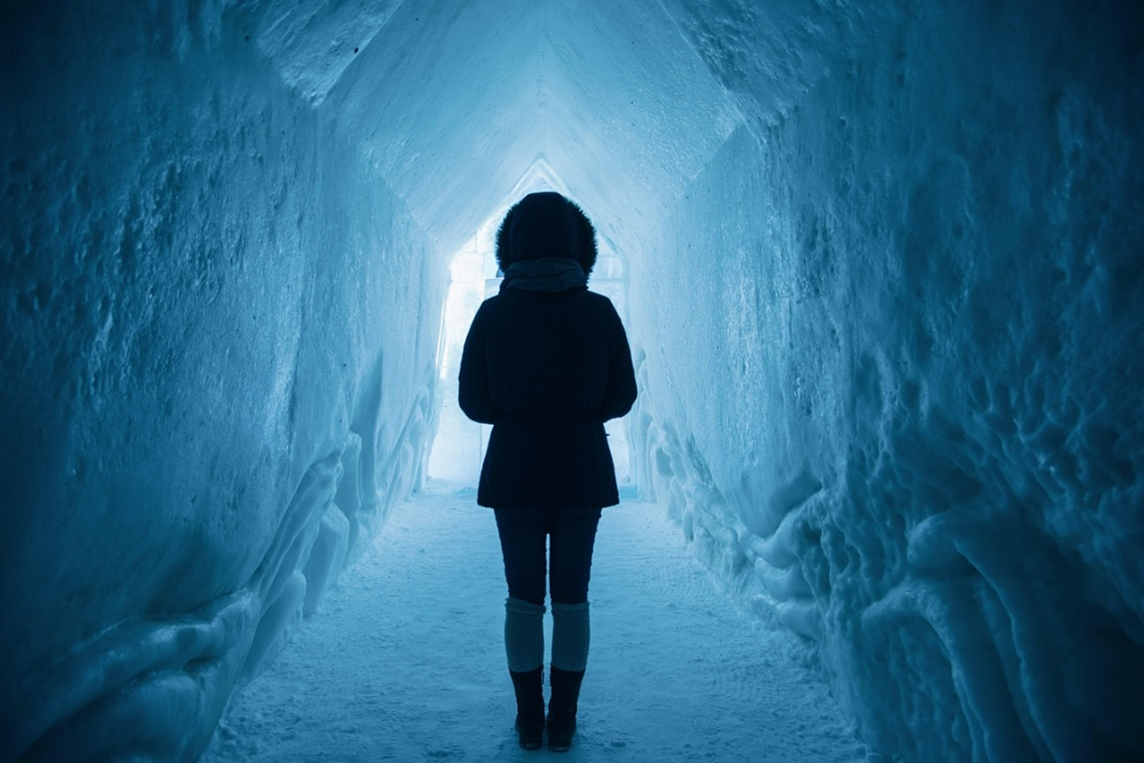Person walking through dark tunnel made of snow