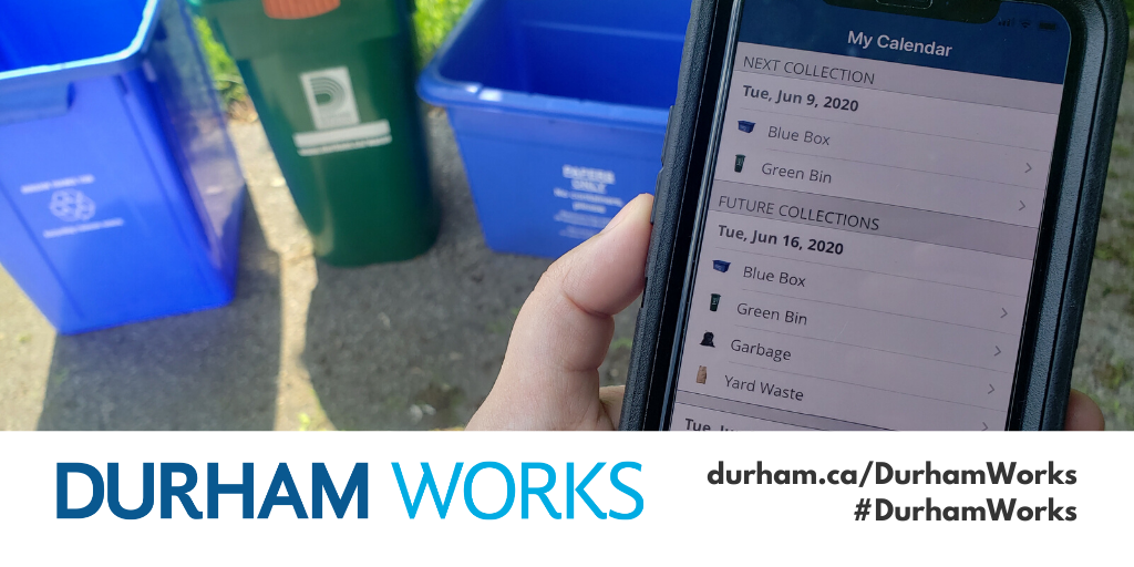 Empty recycling blue boxes and a compost bin in the background, with a cell phone being held in someone’s hand in the foreground and a waste collection schedule being shown on the phone. Text at the bottom of the image states, Durham Works, durham.ca/DurhamWorks, #DurhamWorks.