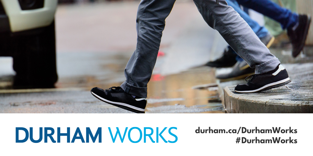 Image shows the legs only of people stepping off the curb in front of a stopped vehicle. Text under image states: “Durham Works, durham.ca/DurhamWorks #DurhamWorks.”