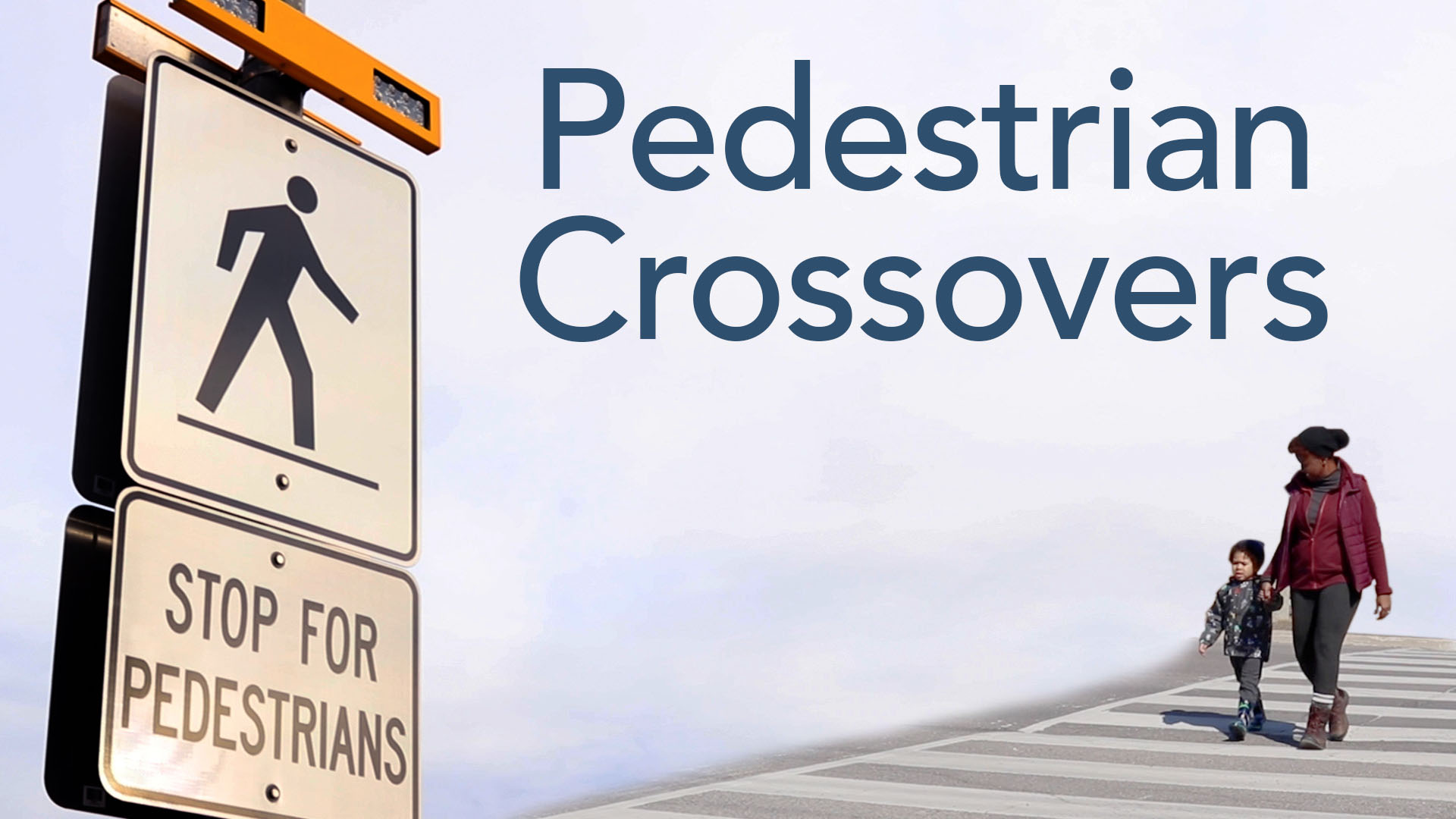 Image shows a mother and son walking across a pedestrian crossover painted on the road with thick white stripes, along with a road sign that says “Stop for pedestrians” and text over the image that states “Pedestrian Crossovers.”