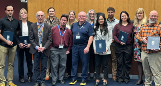 A group of award recipients posing and holding teir certificates.