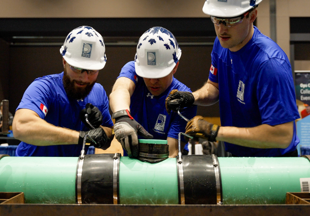 A photo of three Durham Region’s Sludgehammer team members in blue shirts and white hardhats, competing at the 2025 WEAO conference.