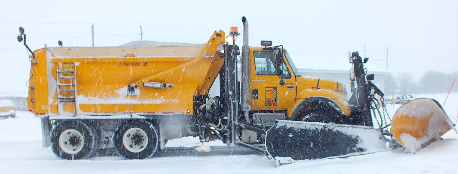 A yellow Durham Region snowplow in snowy weather. 