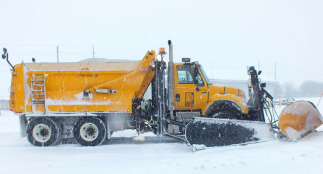 A yellow Durham Region snowplow in snowy weather. 