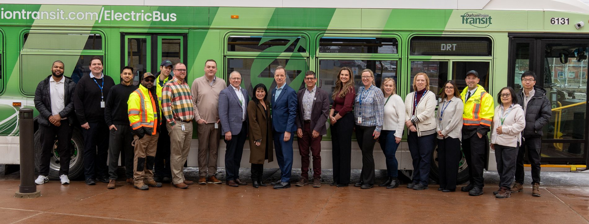 Group of transit workers in front of a green Durham Region Transit electric bus. 
