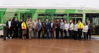 Group of transit workers in front of a green Durham Region Transit electric bus. 