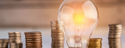 A lightbulb next to a stakc of coins.