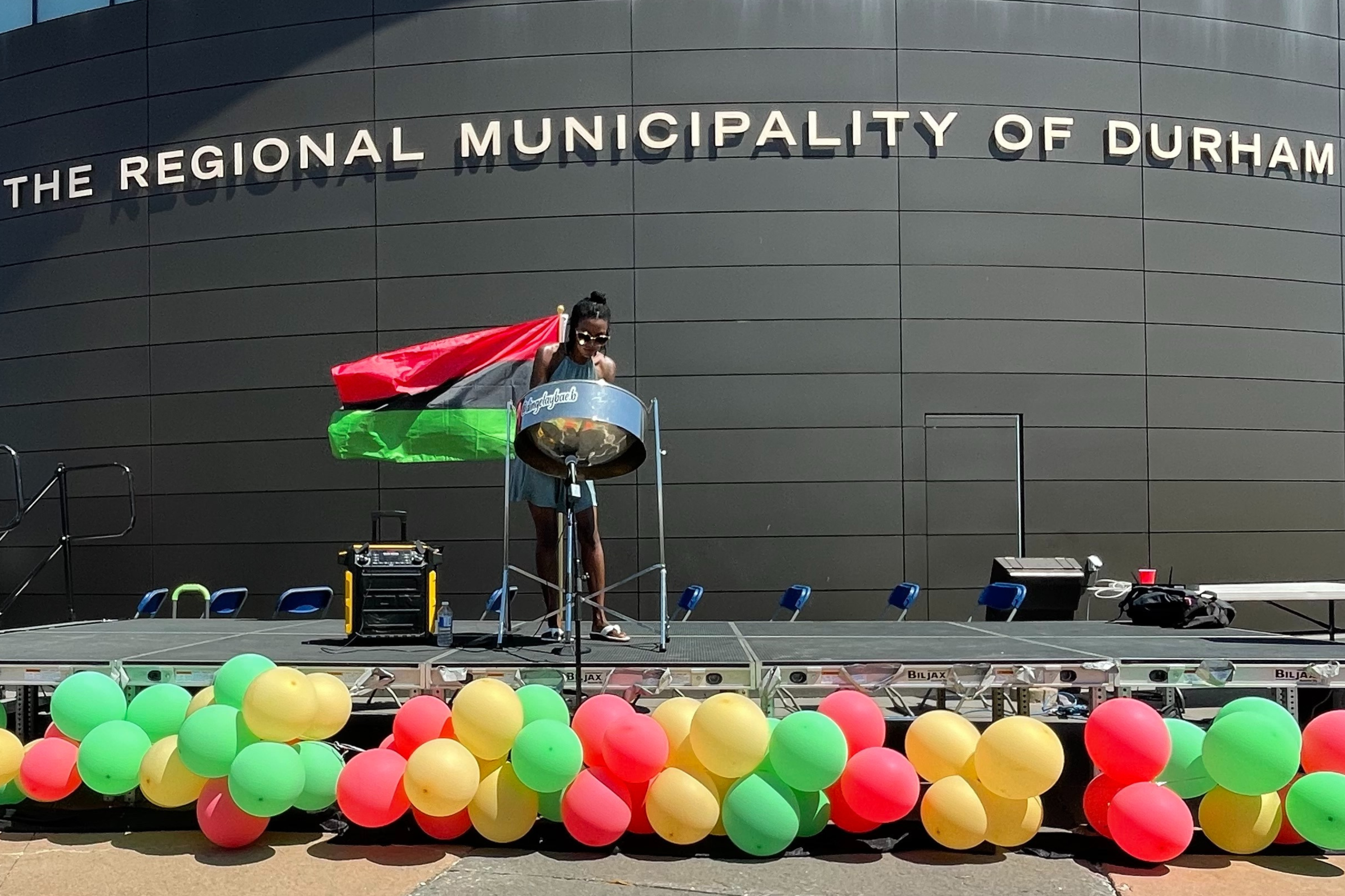 A person playing a steel pan in front of Durham Regional Headquarters