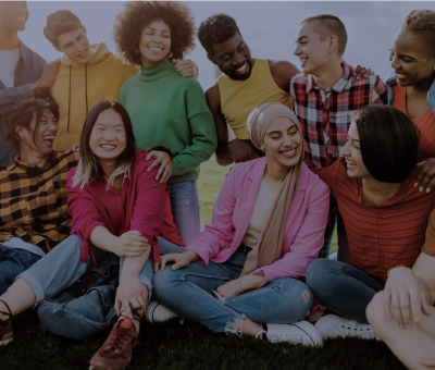 A group of people sitting and standing, smiling at each other.