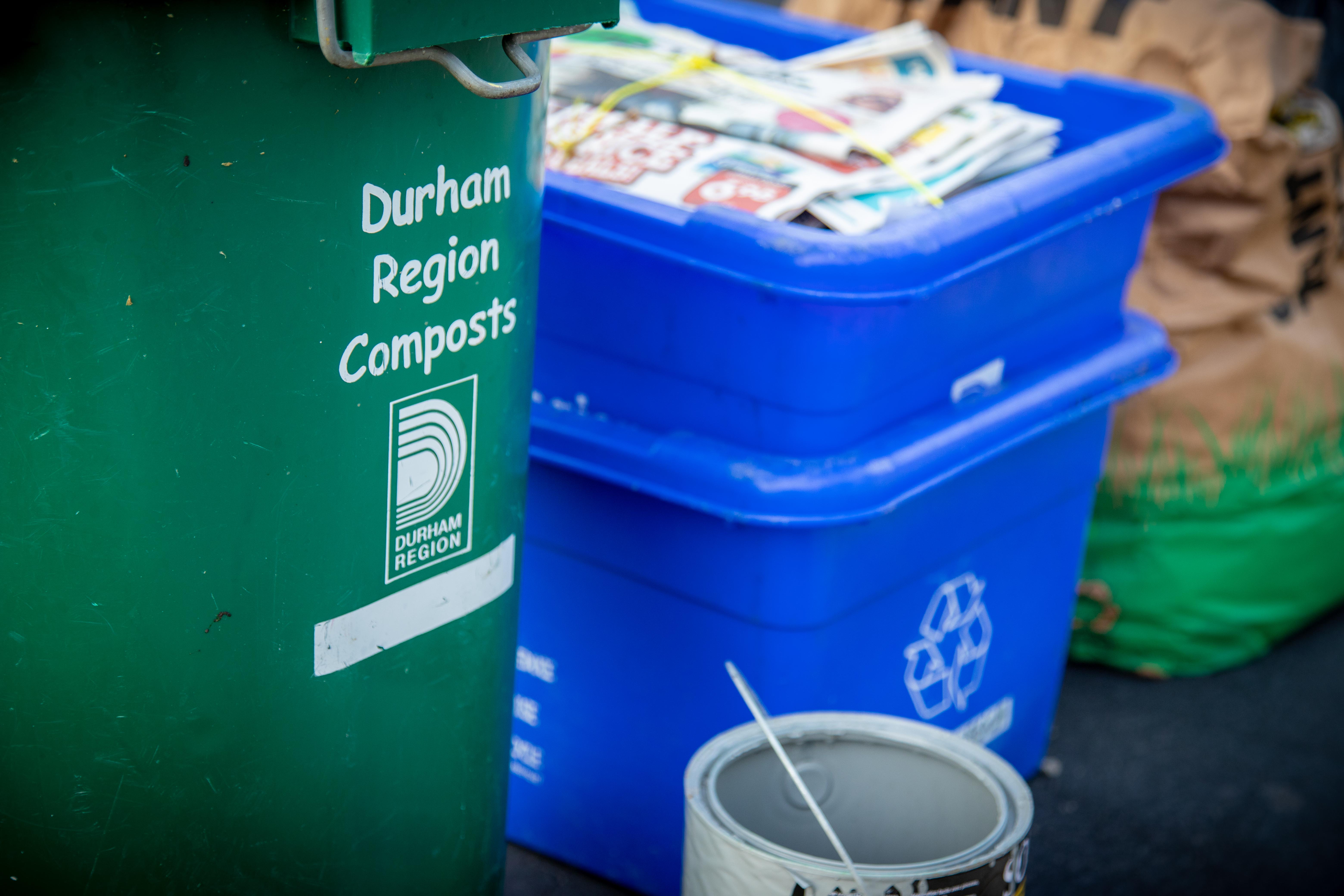 This image is of collection bins at the curb including a blue recycling bin and green compost bin