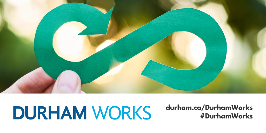 A photo of a hand holding up a circular economy symbol cut out, with a white banner with blue and black text that reads Durham Works durham.ca/waste #DurhamWorks