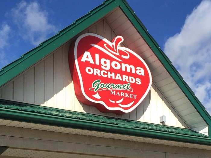 Exterior photo of the Algoma Orchards gourmet market sign on a large red apple