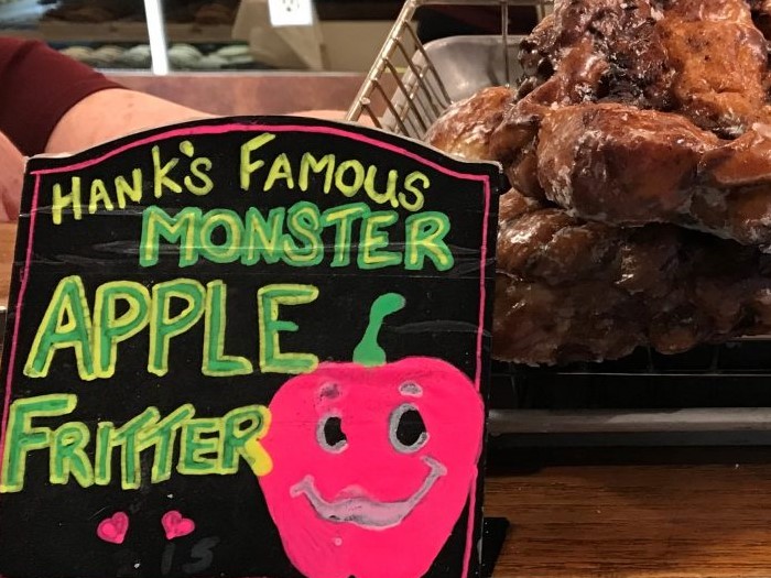 A photo of a sign that says Hanks famous monster apple fritters next to very large fritters