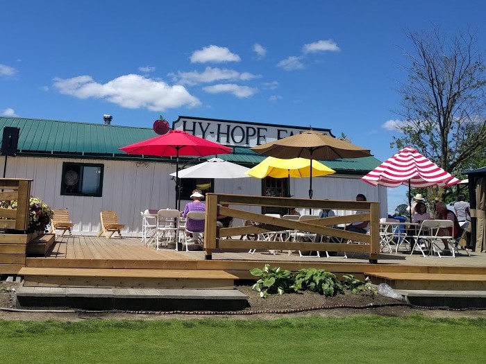 A photo of Hy-Hope Farm and the outdoor patio featuring umbrellas at tables in a variety of colours