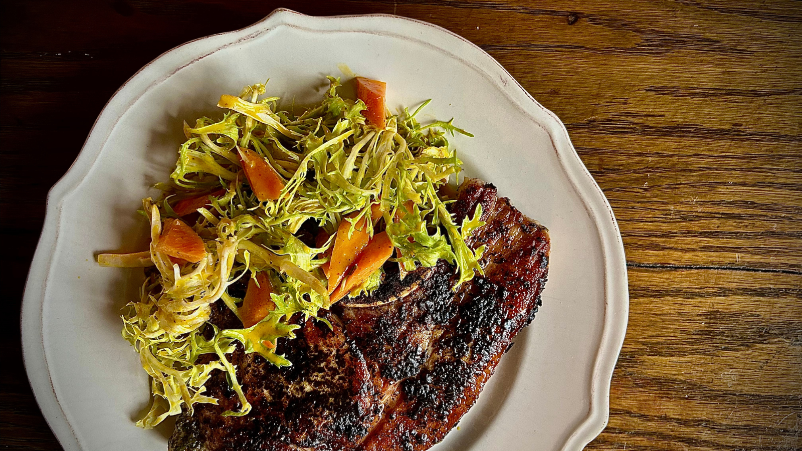 Aerial image of a plate with grilled pork chop and fresh-looking salad