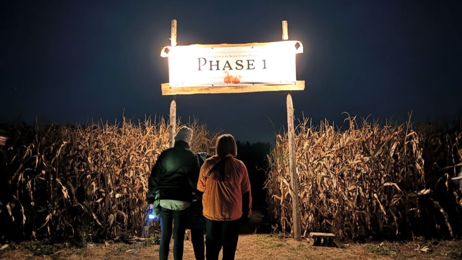 Two people walking into a corn maze at night at Cooper's Farm in Uxbridge, Ontario, Canada.