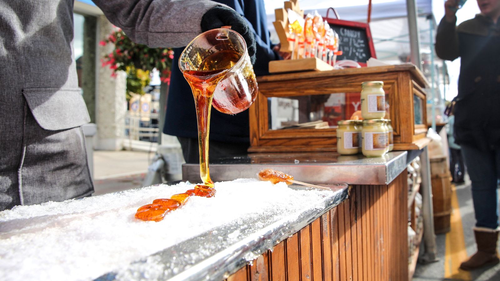 Person pouring fresh maple syrup over ice at Bowmanville Maplefest in Clarington, Ontario
