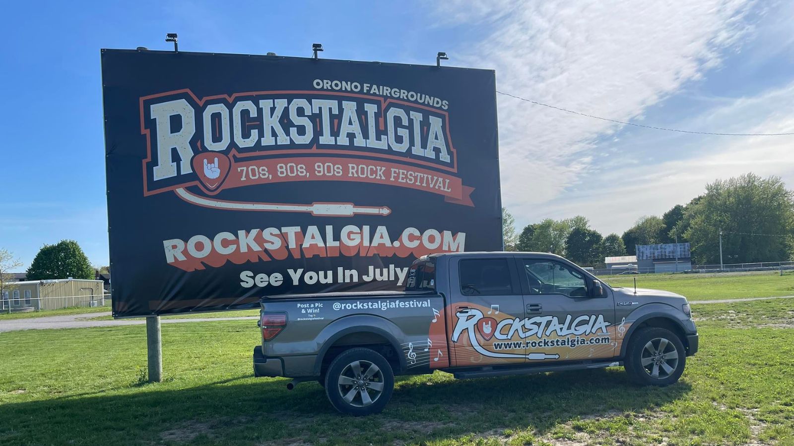 Pickup truck wrapped with Rockstalgia logo and website parked in front of an event billboard 