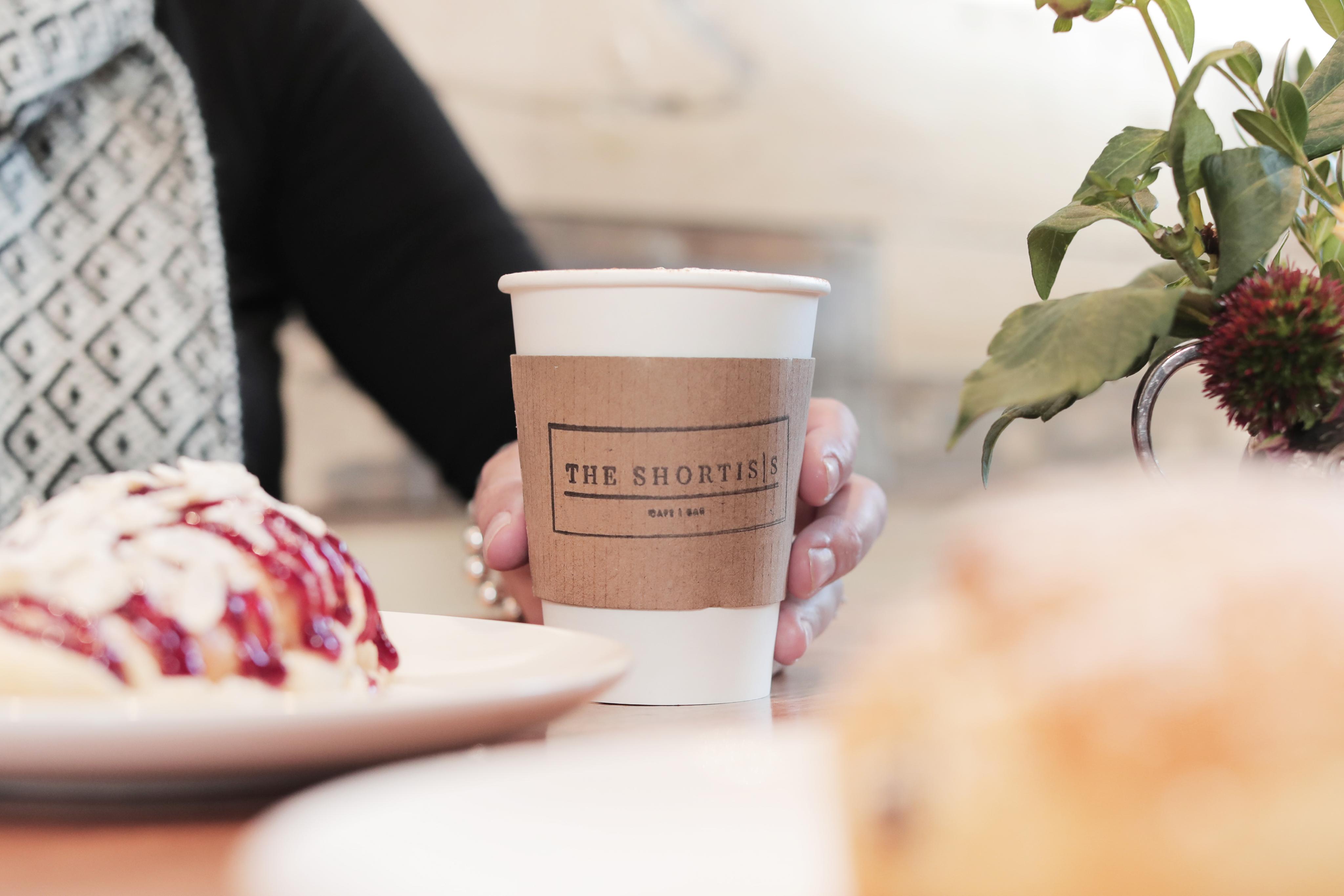 A person holds a coffee at a table in a quaint cafe