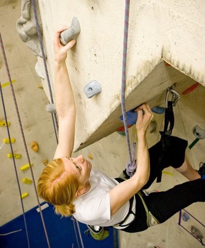 A woman climbing up an indoor climbing wall
