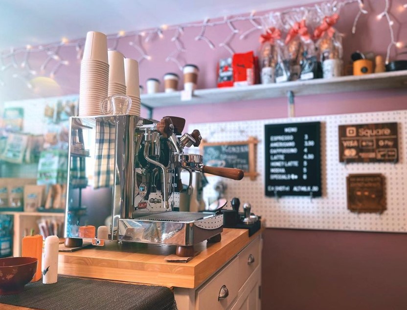 Image of interior of a cafe with an espresso machine on the counter and string lights along the wall