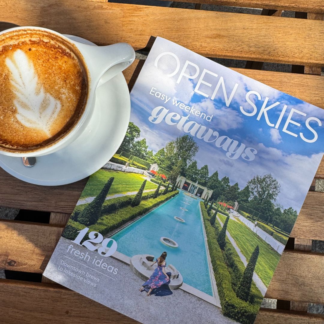 Open Skies magazine cover on table beside frothy cappuccino