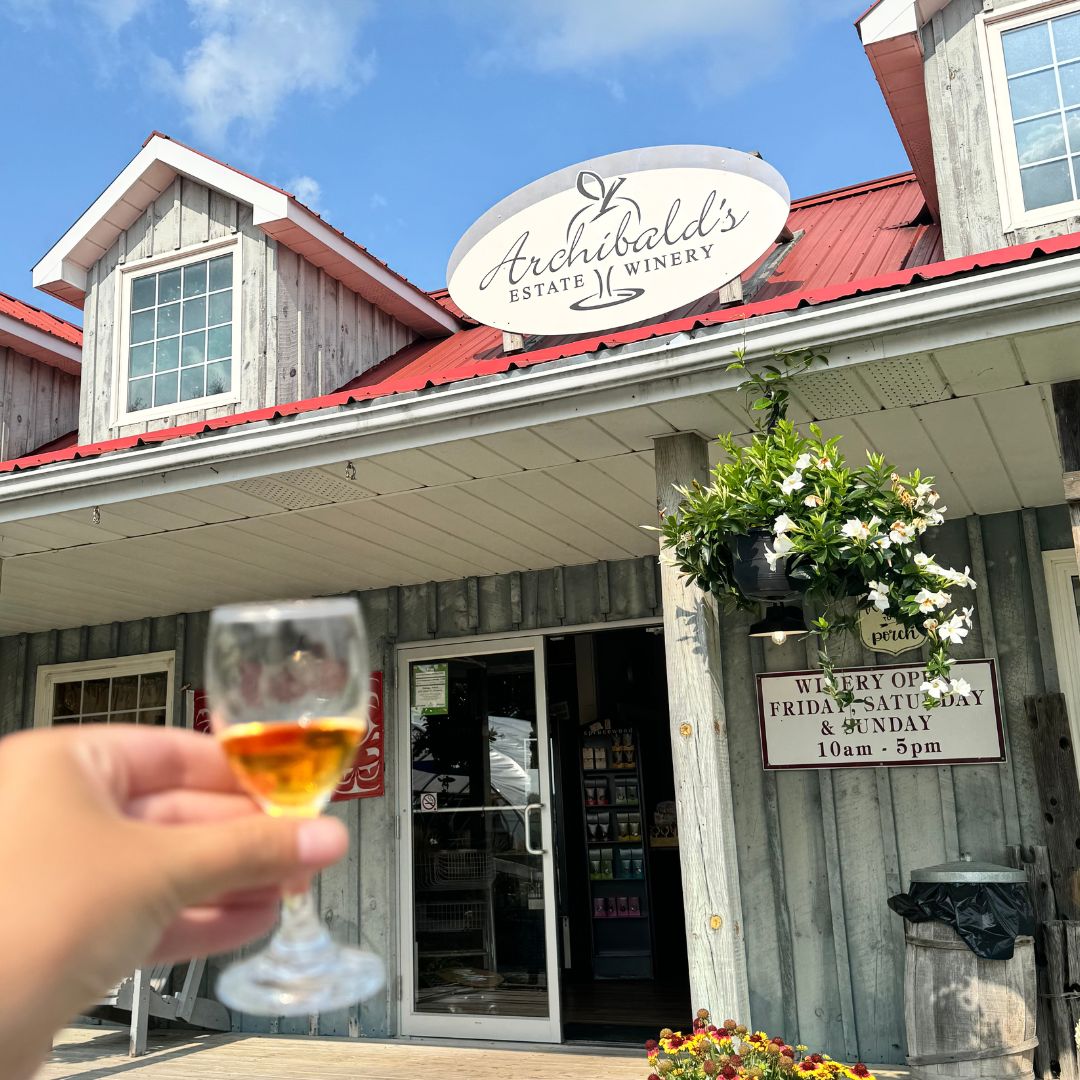 Hand holding a glass of fruit wine at Archibald's Winery in Clarington, Ontario, Canada