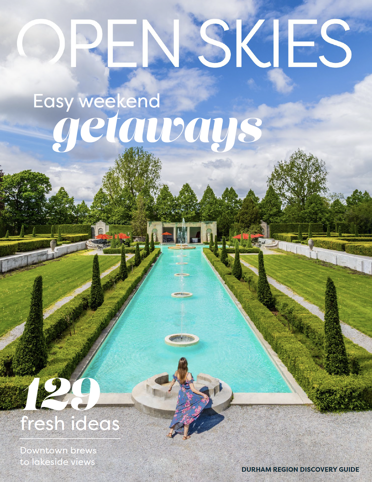 Cover of 'Open Skies' Durham Tourism's latest discovery guide with an image of a woman looking out at the fountain and gardens at Parkwood Estate in Oshawa, Ontario, Canada.