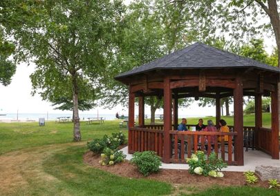 Image of a gazebo at a lakefront park with four people sitting around a picnic table in the centre